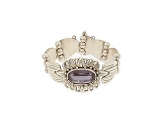 59
A Héctor Aguilar Silver And Amethyst Bracelet
1948-1962; Taxco, Mexico
Stamped: HA / Taxco / 940 / [Eagle 9]
A link bracelet featuring a large sunflower set with an oval hardstone, with pin closure and chain guard
6.5" total inner C x 1.375" H
54.0 grams
Estimate: $400 - $600