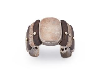 111
A William Spratling Silver And Rosewood Cuff Bracelet
1940-1946, First Design Period; Taxco, Mexico
Stamped for William Spratling; Further stamped: Made in Mexico / Silver
A cuff comprised of alternating rosewood and silver stepped crescent shaped panels with ball rivet terminals
6.5" total inner C x 1.625" H, wrist opening 1.125"
84.9 grams
Estimate: $1,000 - $1,500