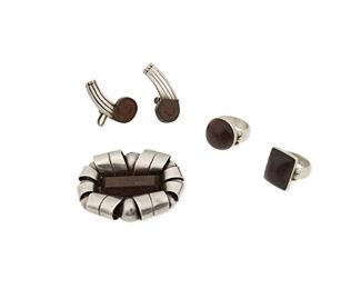 135
A Group Of William Spratling Silver And Rosewood Jewelry
1940-1944, First Design Period; Taxco, Mexico
Stamped for William Spratling; Further stamped: Made in Mexico / Spratling Silver; Earring posts marked: Sterling
Comprised of a brooch with faceted rectangular rosewood set into a curled silver frame (1.75" H x 2.25" W); a pair of unmarked wave motif screw-back earrings (0.625" L x 1.5" W) and two rosewood set rings, one round (ring size: 9) and one rectangular (ring size: 9.5)

5 pieces
77.5 grams gross
Estimate: $800 - $1,200