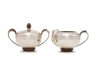 141
A William Spratling Rosewood And Sterling Silver Cream And Sugar Set
1945-1946, First Design Period; Taxco, Mexico
Each stamped for William Spratling; Further stamped: Sterling
Each smooth silver body with applied silver ribbing and issuing carved rosewood handles, further adorned with carved rosewood accents, 2 pieces
Creamer: 3.128" H x 5.25" W x 3.875" D; Sugar: 4.25" H x 6.125" W x 3.875" D
19.255 oz. troy approximately
Estimate: $400 - $600