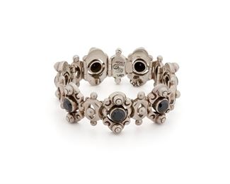 200
An Antonio Pineda Sterling Silver And Onyx Bracelet
1953-1979; Taxco, Mexico
Stamped with crown mark for Antonio Pineda; Further stamped: [Eagle 17] / Hecho en Mexico / Silver / 970
The ornamental bracelet featuring hinged links set with faceted round onyx, alternating with smaller silver links
7.125" L x 1" H
101.1 grams
Estimate: $800 - $1,200