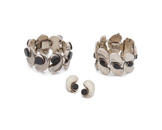 220
A Group Of Antonio Pineda Sterling Silver And Onyx Jewelry
1953-1979; Taxco, Mexico
Crown mark for Antonio Pineda; Each variously stamped: [Eagle 17] / Hecho en Mexico / 970 / Silver / ZZ515 / Made in Mexico
Comprising two similarly-styled bracelets consisting of silver waves alternating with round onyx (7" L x 1.75" H and 7" L x 1.5" H) and a matching pair of screw-back earrings (1.125" L)

4 pieces
269.5 grams gross
Estimate: $1,200 - $1,800