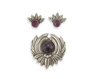 300
A Set Of Los Castillo Silver And Amethyst Jewelry
1940-1945; Taxco, Mexico
Each stamped: Los Castillo / Taxco / Sterling / Made in Mexico; Further stamped: [Brooch] 298P / [earring] 298E
A brooch and a pair of clip earrings designed with stylized petals and each set with a central amethyst cabochon.

3 pieces
Brooch: 2" H x 1.875" W; Earrings: 0.875" L x 1" W
36.8 grams gross
Estimate: $200 - $400
