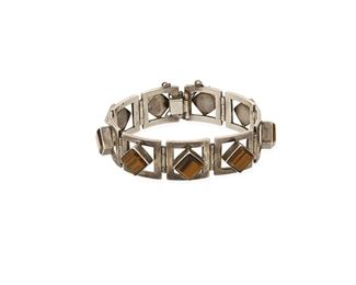334
A Miguel Melendez Stone-Set Link Bracelet
Second Half 20th Century; Taxco, Mexico
Stamped with conjoined MC; Further stamped: Taxco / Sterling / Hecho en Mexico / [Eagle 3]
An openwork square link bracelet set with square tiger's eye stones, with clasp closure and chain guard
7" L x 0.75" H
54.0 grams
Estimate: $200 - $300