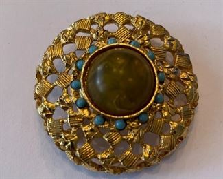 Gold broach with turquoise accents.