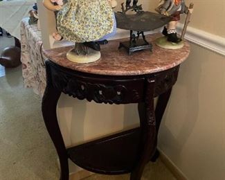 . . . a Victorian-style wall table with Hummel doll and faux Hummel on top