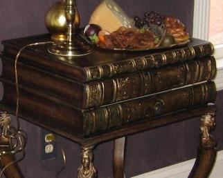 Unique stacked books lamp table with hidden drawers and storage compartment. Egyptian kings heads on scrolled clawed feet legs   Antique brown with gold accents. Dimensions: 20 “ w x 16 “ deep x31 “ high.