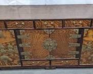 This narrow and low-format vintage Chinese wood tea cabinet features antiqued brass decorative hardware. It was used as a TV stand, and some surface marks are shown. The inner chambers are papered with Chinese writing and are surrounded by seven small, flat drawers. Interesting round thumb catches open side well-type chambers. The cabinet measures 39" long x 14" deep x 18.5" tall. The center chamber is 13" high x 18.5" long x 10.5" tall.
