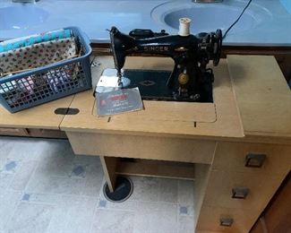 Antique Singer sewing machine and cabinet.  Has attachments.