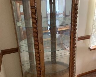Curved curio cabinet with interesting trim work and mirrored back