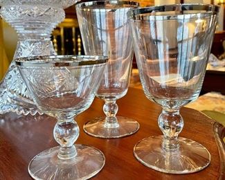 3 sets of different sized silver-rimmed glassware; 7 champagne at $42; 8 white wine at $48; 7 red wine at $42; also set of 8 salad plates at $32