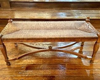 $400; 2-seat, distressed pine bench with rush seat above 4 legs and a double Y-stretcher plus custom silk, striped cushion (has some small holes); 42”w x 17”d x 19”h