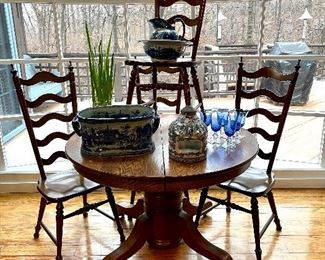 $200; vintage, round, oak table with one leaf and pedestal base; plus four ladder-back chairs; table: 44”d x 29”h; with leaf 54”w; chairs: 16”w x 17”d x 46”h