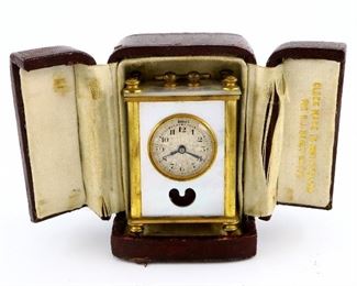 A miniature Lancel, Swiss carriage clock.  30 hr time only movement with Silvered dial and Arabic numerals.  Gilded Brass case with Mother-of-Pearl panels and original leather travel case.  Wear, wound tight, not running when cataloged.  ESTIMATE $200-300