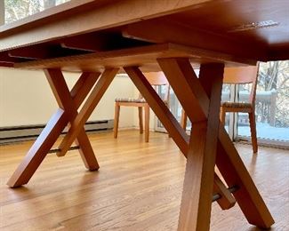 Trestle table with angled crossbeams and a steel support rod