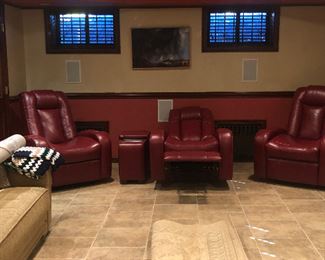 Three movie-theater style recliners with cup holders and a side table