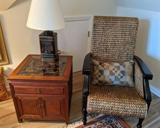 One each of a pair of woven rattan armchairs, Asian wooden side table, with hand-carved top detail and glass top to protect the carving and vintage Frederick Cooper Asian tea tin lamp.