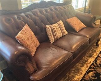Brown leather sofa with carving, tufted back, and nail-head trim