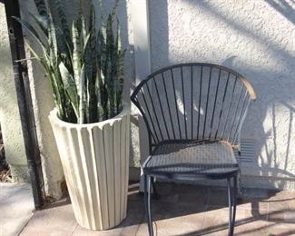Large ceramic pot with cactus. Iron chair.