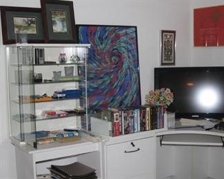 TV, table top glass curio, DVDs, artwork, white filing cabinet.