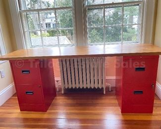 Desk of two red Hon filing cabinets and slab door