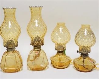 1117	4 AMBER FOSTORIA COIN GLASS OIL LAMPS, TWO ARE CHAMBER LAMPS. TALLEST 14 IN H 
