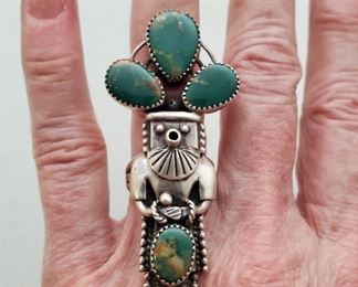 Vintage Navajo Silver & Turquoise Kachina Ring. Size 6 3/4. Sterling silver ring is 2 5/8" long and 1 1/8" wide. It is set with deep green turquoise stones, and is signed with a curved arrow pictograph. I have not been able to identify the artist.