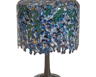 1003
A Tiffany-Style Leaded Glass Table Lamp
Fourth-Quarter 20th Century
Engraved in script to one glass panel: R. Kopf 8/81
The polychrome leaded glass wisteria-style shade on a four-light patinated bronze trunk-form base, electrified
Overall: 28" H x 18" Dia.
Estimate: $1,000 - $1,500