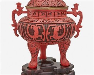 1268
A Chinese Cast Resin Censer
20th Century
The cast resin, cinnabar-colored censer with wide-shouldered body fitted with two free-form handles surmounted by a fu dog finial to the lid, raised on three shaped legs and set atop a tri-form carved wood stand
14.25" H x 11.5" W x 9.25" D
Estimate: $500 - $700