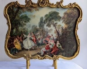 Roccoco Style Fireplace Screen. Featuring a lovely print of the “La Camargo  Dancing”. Made in England.

There is some light wear on the painted wood that can be seen in the photos. Measures 26” x 26”.