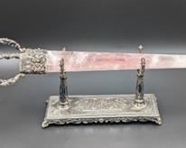 Decorative Rose Quartz Sword or Dagger and Stand. A truly beautiful piece with a intricate bejeweled handle! There are no markings and the stand appears to be silver plated. The sword measures 17” lying and 2” wide at the largest portion.