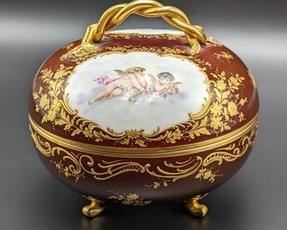 Covered Painted Porcelain Cherub Tooted Dish. There is some light paint wear, but in overall great condition. Measures 6” in diameter and 4.5” high.