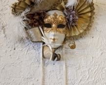 Venetian Carnival Face Mask. Pretty gold with feather accents. Signed by the artist and stamped Italy. Includes the ribbons and measures 16” wide and 14” high.
