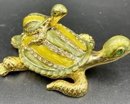 This jeweled trinket box with a cute little baby on its back measures 3.5 inches wide