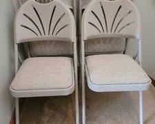 Set of four folding chairs in a beige composite material with beige upholstered seats and decorative back rests