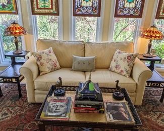 Cozy sunroom, with sleeper sofa, stained glass panels, pair of hand-painted black lacquer two-tiered Chinoiserie end tables, stained glass lamps and John Widdicomb faux bamboo coffee table, w/gold-leafed top.