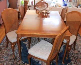 Cane back dining chairs and dining table that has two leaves.