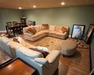 Beige color three-piece leather sectional. Beige color full size leather sofa.  Extra large projection screen. Framed movie posters. Several area rugs. 