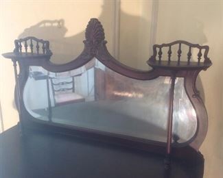 Dining Room:  This is the top section of the delicate display cabinet.  Notice the beveled mirror and spindle shelf rails that flank the center carved shell.