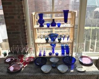 Sun Room:   Red salad/dessert plates and red dinner plates are on the left with red/clear stems.  More clear/red stems are on the right.  Many of the red glass items are from Crate & Barrel.  In the center is a nice selection of cobalt blue glassware and blue/white Chinese ceramic bowls.