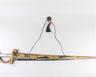 Lot 4: Early 20th C Swordfish Bill Sword, Signed MB Simmons. An extensively decorated swordfish bill sword, signed "MB Simmons" and "October 7 1907." Carved and painted with two steam boats and a sword fish. American flag and crest at the ricasso. The hilt is made of carved and painted wood. Acquired in the 1980s near Boston. From the collection of Barbara Porter & Robert Wincuinas.

Dimensions are 6 in h x 43.5 in w x 1 in d. Condition is good. Overall surface wear. Please call or email for a detailed condition report.