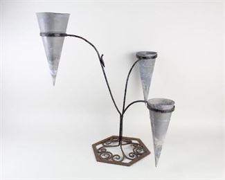 Lot 74: Wrought Iron & Tin 3 Armed Candle or Flower Stand. Three iron arms branch up from six sided iron base with wrought curlicues. Each arm holds a conical tin cup. Fill each cup with dried flowers for a unique decoration.
 
Dimensions are 24.5 in h x 20.5 in w x 20.5 in d. Condition is good. Please call or email for a detailed condition report. 