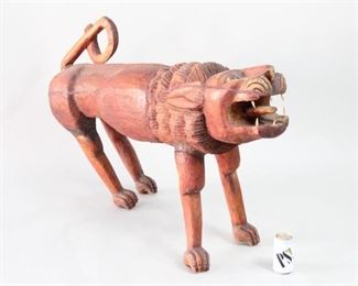 Lot 78: Large Haitian Carved Wood Lion Sculpture Statue(1/2). Wonderfully carved, stylized lion in red stained wood. Expressive face with fully carved out mouth and six teeth in contrasting wood. Acquired in the 1980’s, Haiti. This is the first out of two lots of similar lion sculptures. From the collection of Barbara Porter & Robert Wincuinas.

Dimensions are 29 in h x 12 in w x 44 in d. Condition is good. Surface wear throughout. Crack through lower jaw. Central crack running along side body. Cracks where legs connect to body. Cracks on tail. Back legs tilts to one side. Please call or email for a detailed condition report.