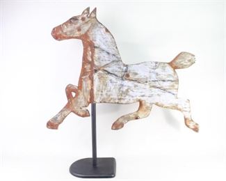 Lot 86: Primitive Folk Art Running Horse Metal Weather Vane. Weather vane, once white painted with black details and harness, with great patina. Mounted on a new stand. Acquired in the 1970s, Bennington, Vermont. From the collection of Barbara Porter & Robert Wincuinas.

Dimensions are 37 in h x 36 in w. Condition is fair to good. Surface wear and rust throughout. Some holes. Please call or email for a detailed condition report.