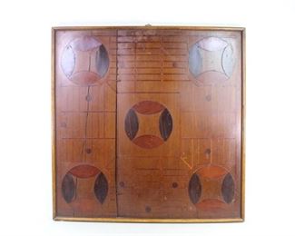 Lot 88: Folk Art Painted Wood Inlaid Pattern Parcheesi Game Board. A beautiful, handmade Parcheesi game board made of 3 differently colored types of wood. Framed in oak and will a metal ring at the top for hanging on the wall as art.
Dimensions are 25 in h x 24.25 in w x 1.25 in d. Condition is fair with cracks & inlay pieces separating, surface wear, a light stain on top and a crazed effect throughout the wood surface. Please call or email for a detailed condition report.