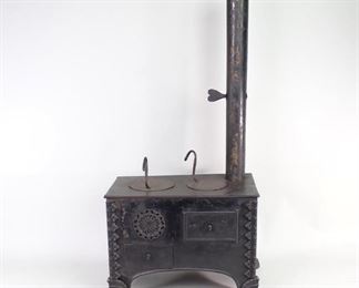 Lot 94: Primitive Black Metal Miniature Toy Kitchen Cook Stove. Darling handcrafted miniature cookstove has a stovepipe with a heart shaped damper knob, a door that opens to reveal an oven, and 2 removable burners with handles. Body is fabricated from sheet metal, standing on Victorian style ornate cast iron claw feet. Fantastic item to use decoratively in your kitchen or business. From the collection of Barbara Porter & Robert Wincuinas.

Dimensions are 30 in h x 14 in w x 10 in d. Condition is good. Please call or email for a detailed condition report.