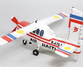 Lot 104: Lionel Simonis Haitian Folk Art Papier Mache. Fabulous and detailed large papier mache Air Haiti Plane is vibrantly painted and signed L. Simonis 1988. Acquired in Haiti. Suspend from a high ceiling as eye-catching sculpture.From the collection of Barbara Porter & Robert Wincuinas.

Dimensions are 28 in h x 54 in w x 46 in d. Condition is good. Please call or email for a detailed condition report.