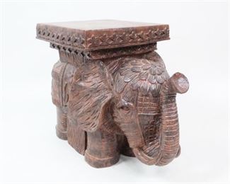 Lot 116: Small Hand Carved Wood Elephant Side Table Base. Elephant has a platform on its back, which becomes the surface for a small table. Flat top also allows it to be used as a base for another surface like a fitted piece of glass, or platform for display. Richly carved textures in animal skin and adornments are accented by light on glossy finish.

Dimensions are 18 in h x 22.5 in w x 17.75 in d. Condition is very good, with very minor marks on top. Please call or email for a detailed condition report.