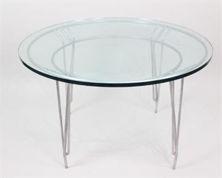 Lot 119: Contemporary Art Deco Style Round Glass Coffee Table. Sleek and decorative aluminum base with a thick glass top. The base has a eye catching design in an Art Deco style with the four legs mounted on two circular frames. A classic design that would look great in a variety of interiors. 
Dimensions are 26.25 in h x 43 in w x 43 in d. Dimensions for base are 25.25 in h x 40 in w x 40 in d. Dimensions for glass top are 0.75 in h x 43 in w x 43 in d. Condition is very good. Slight surface wear throughout. Some scratches to glass. Drill holes on metal base. Please call or email for a detailed condition report.