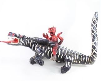 Lot 122: Carved Mexican Day of the Dead Devil Dragon Sculpture. Sculpture of a devil riding a dragon. Carved out of a light weight wood and painted in red, black and white. The devil and dragon are made as separate pieces and are detachable. Acquired in the 1980s, Mexico. From the collection of Barbara Porter & Robert Wincuinas.

Dimensions are 23 in h x 19 in w x 34 in d. Condition is good to very good. Surface wear and scuffs throughout. Horns of the devil are scuffed. Some small cracks in wood. Minor paint chipping. Please call or email for a detailed condition report. 